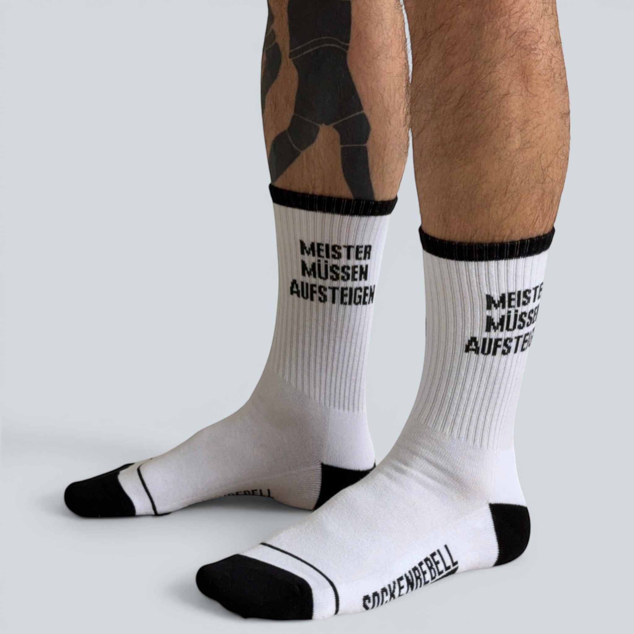 SOCKENREBELL white crew socks with black trim and text "MEISTER MÜSSEN AUFSTEIGEN".
