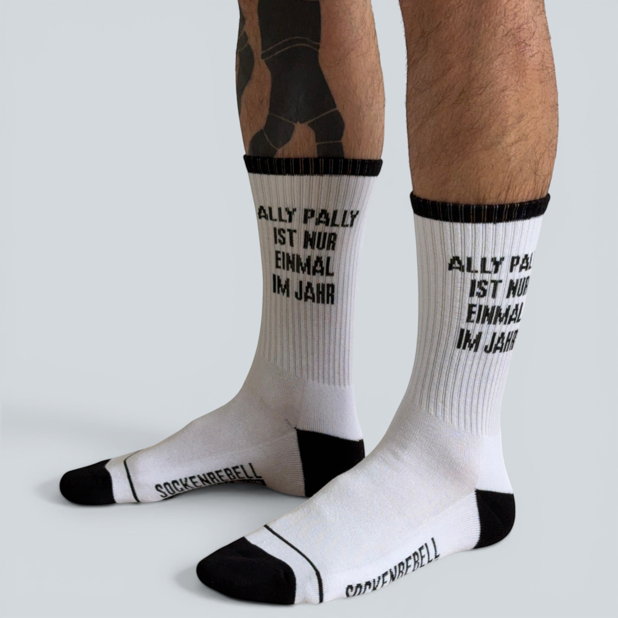 SOCKENREBELL white crew socks with black trim and text "ALLY PALLY IST NUR EINMAL IM JAHR".
