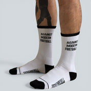 SOCKENREBELL white crew socks with black toe and heel, featuring "AGAINST MODERN FOOTBALL" text.