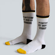 SOCKENREBELL white crew socks with black and yellow accents and the text "PYROTECHNIK IST DOCH KEIN VERBRECHEN" printed on them.