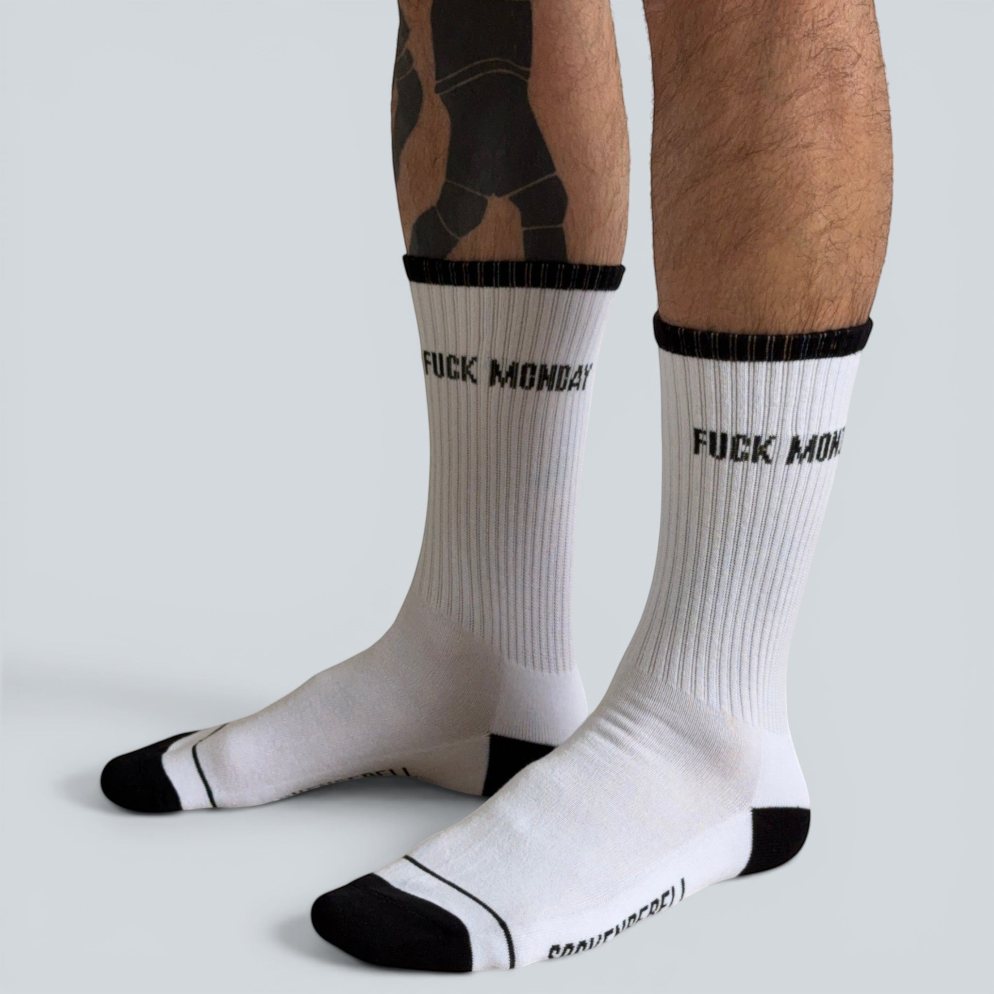 SOCKENREBELL white crew socks with black trim and "FUCK MONDAY" text. Cotton blend.
